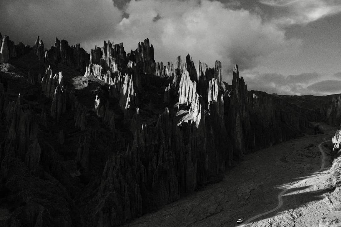 hillsides of rock eroded into spires under clouds, in black and white