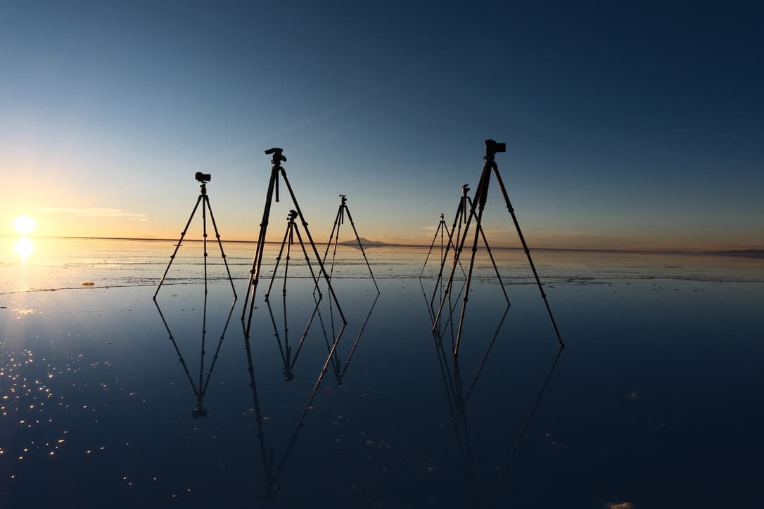tripods reflected in water over the salt, at dusk