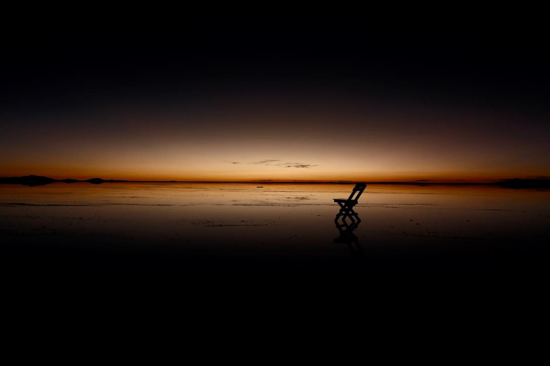 a folding chair silhouetted against the last light on the horizon