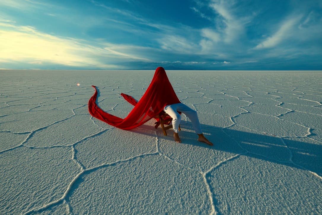 a seated person arched backward and covered by a red cloth, on the salt