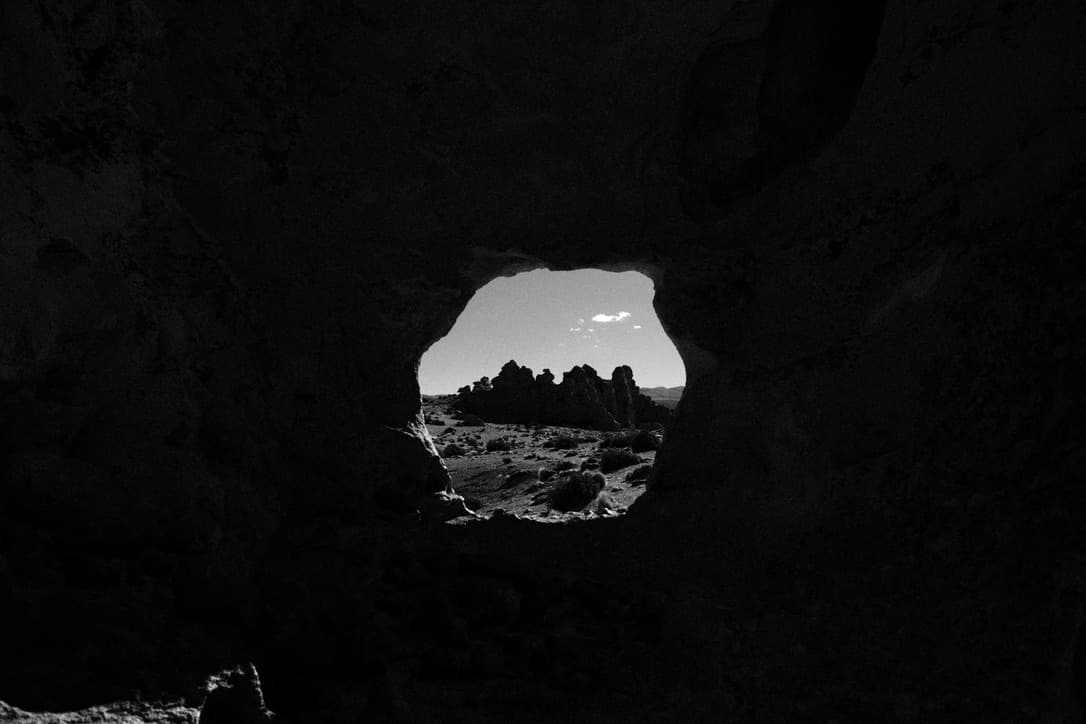 an opening in the rock frames formations in the distance, in black and white