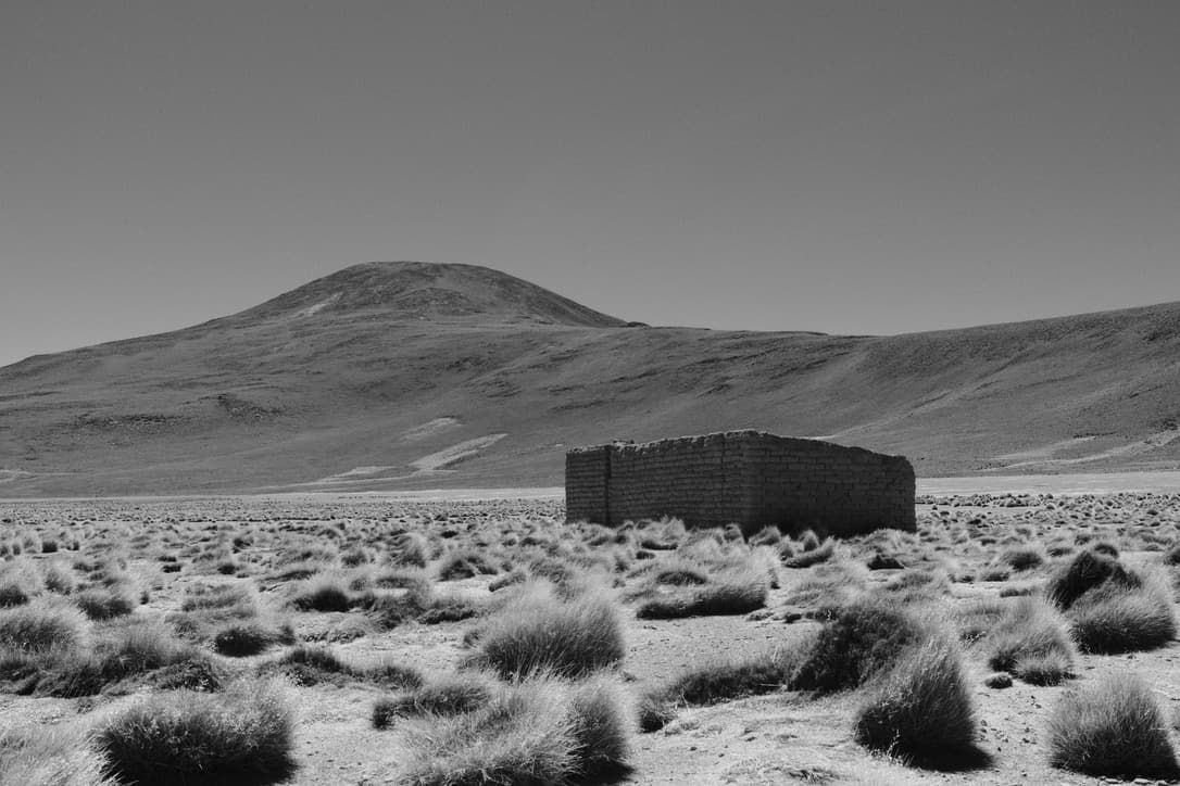 a roofless stone enclosure on a grassy plain, in black and white