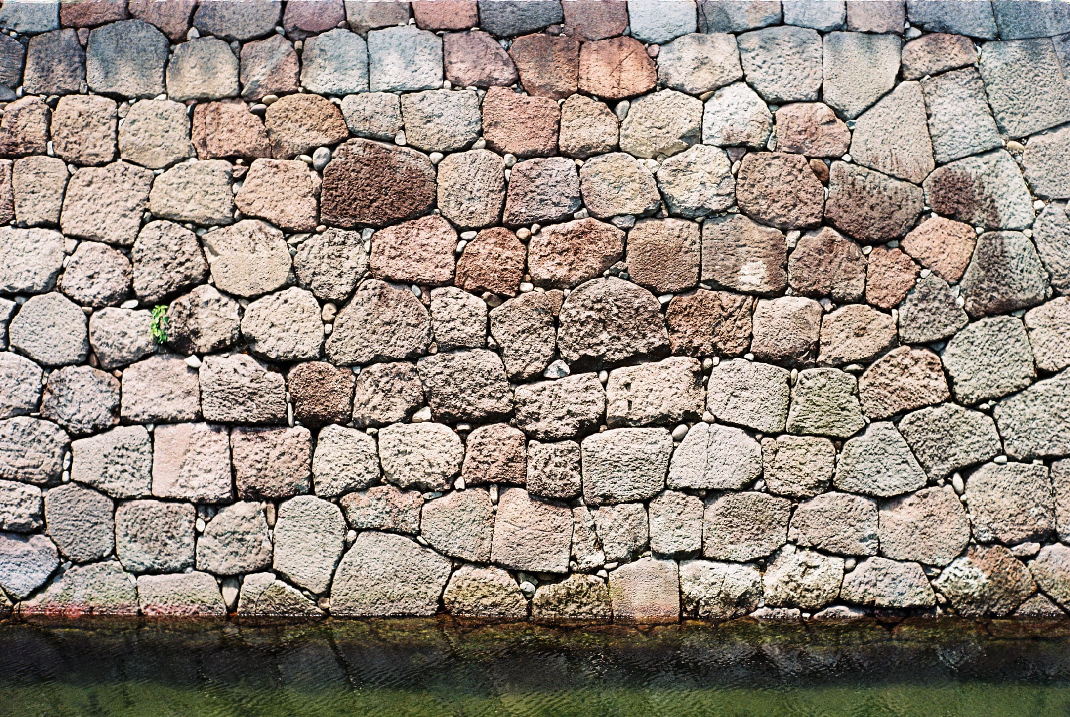 a wall of tightly fitted irregular stones, with grass at its foot