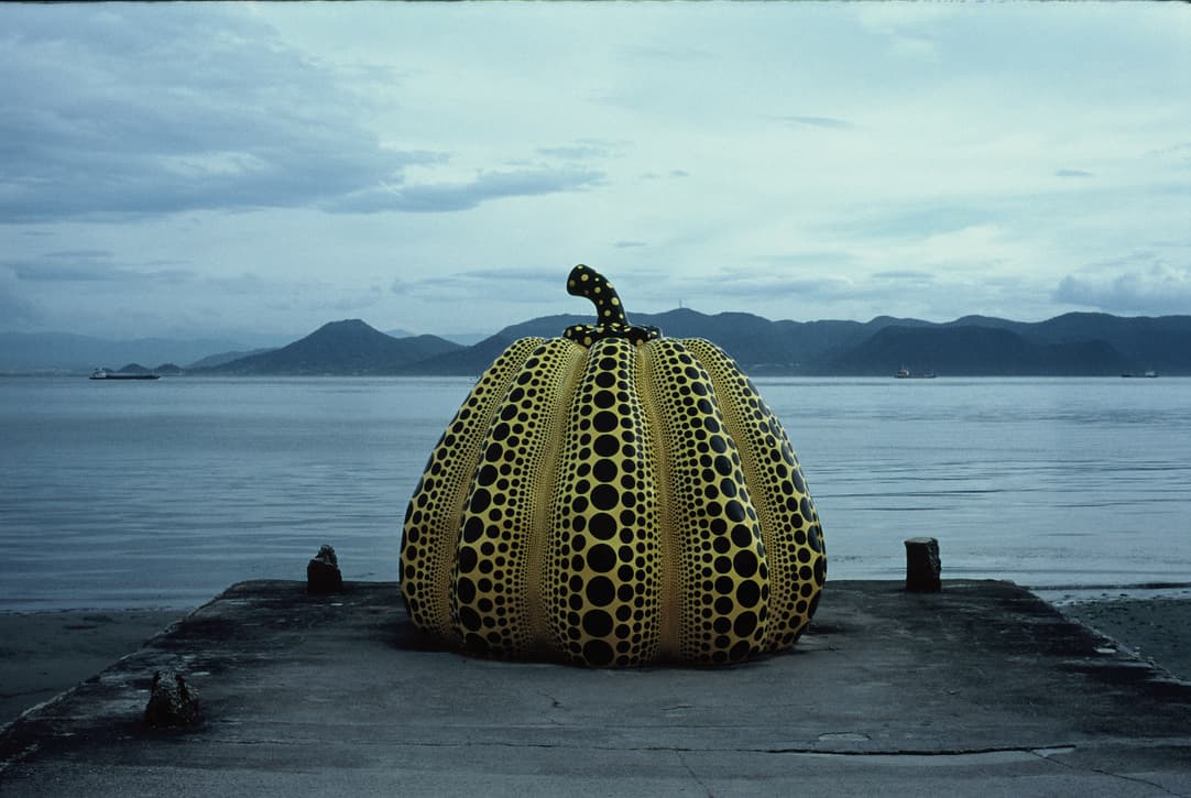 the dotted pumpkin at the end of the pier, under an overcast sky with islands behind